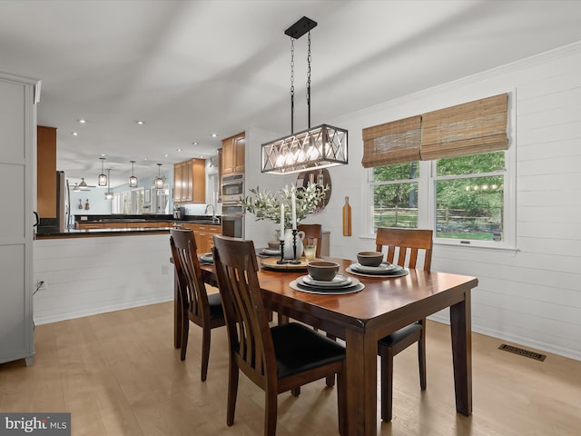 dining space featuring light wood-style flooring and wood walls