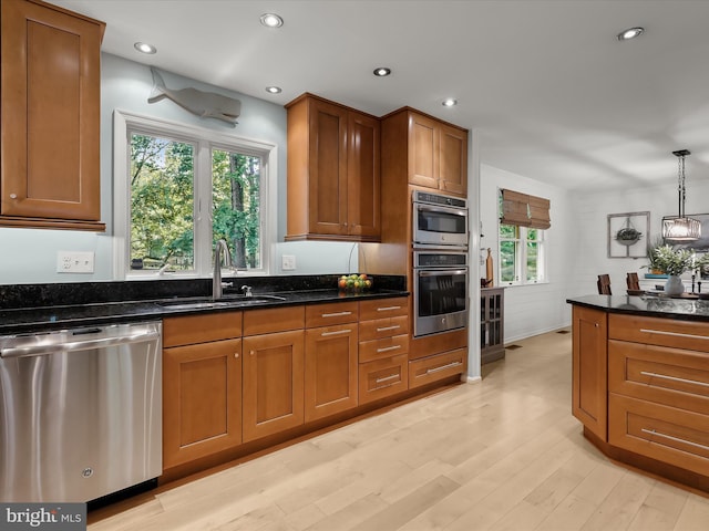 kitchen featuring appliances with stainless steel finishes, a sink, brown cabinetry, light wood-style flooring, and recessed lighting