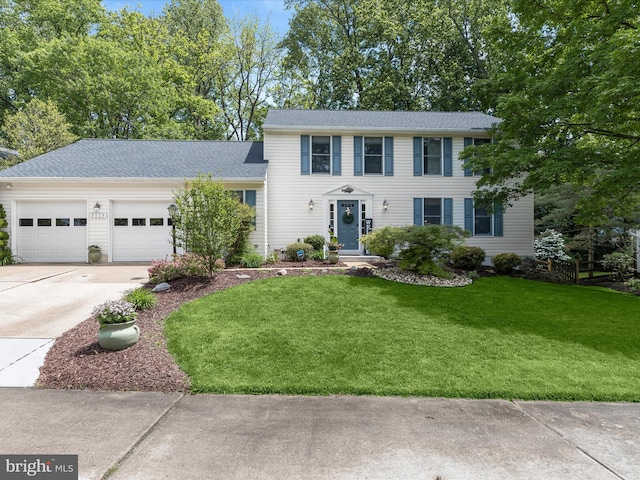 colonial house with concrete driveway, an attached garage, and a front yard