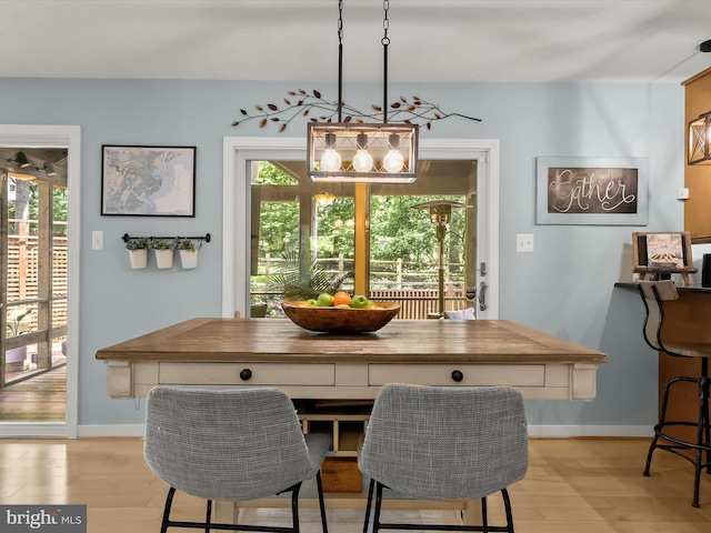 dining area with light wood-type flooring and baseboards