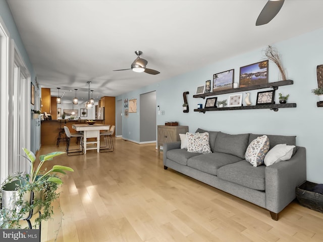 living room with ceiling fan, light wood finished floors, and baseboards