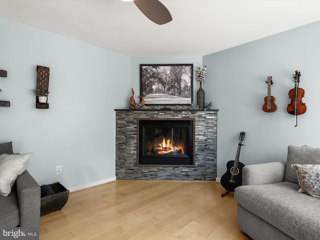 living area with wood finished floors, a tiled fireplace, and baseboards