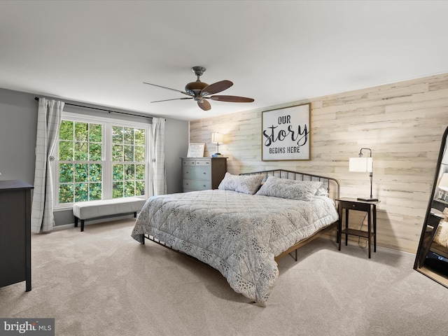 bedroom featuring wooden walls, carpet flooring, and ceiling fan