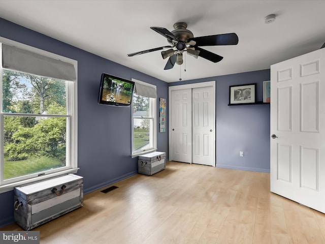 bedroom with multiple windows, light wood finished floors, and baseboards