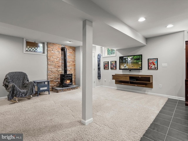below grade area with a wood stove, baseboards, dark carpet, and recessed lighting