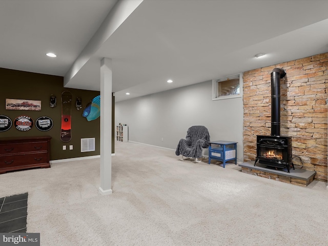 finished below grade area featuring carpet flooring, a wood stove, baseboards, and recessed lighting