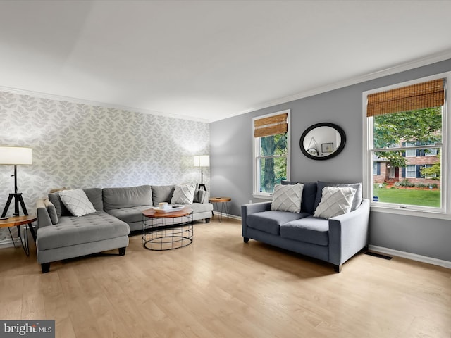 living room with wallpapered walls, light wood-type flooring, crown molding, and baseboards