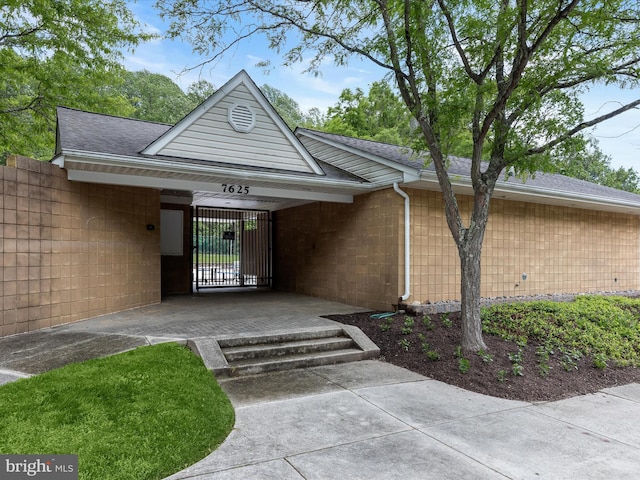 entrance to property featuring a shingled roof and fence