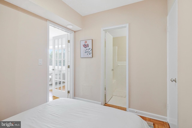 bedroom featuring wood finished floors, baseboards, and connected bathroom