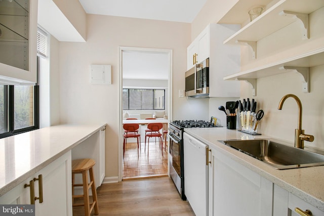 kitchen with light wood-style flooring, a sink, white cabinetry, open shelves, and appliances with stainless steel finishes