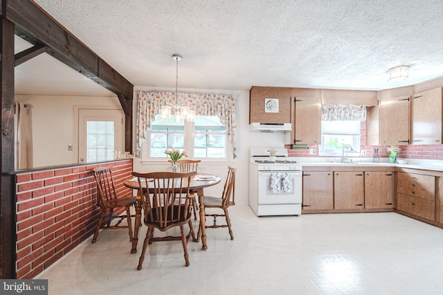 kitchen featuring a textured ceiling, under cabinet range hood, light countertops, and white gas stove