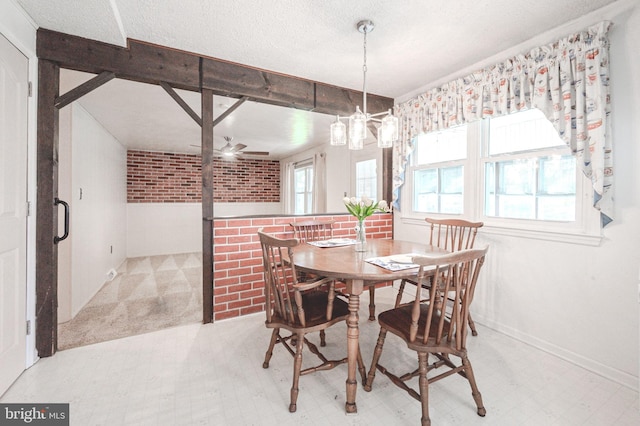 dining area featuring brick wall, an inviting chandelier, light floors, and a textured ceiling