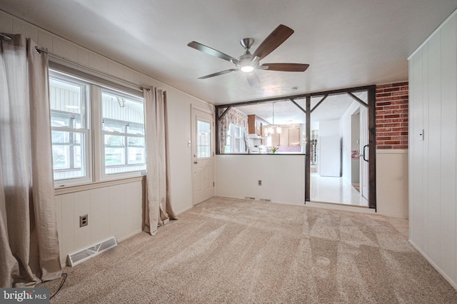 carpeted empty room featuring a wealth of natural light, visible vents, and a ceiling fan