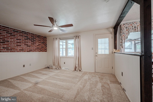 spare room with visible vents, ceiling fan, carpet, and a wainscoted wall
