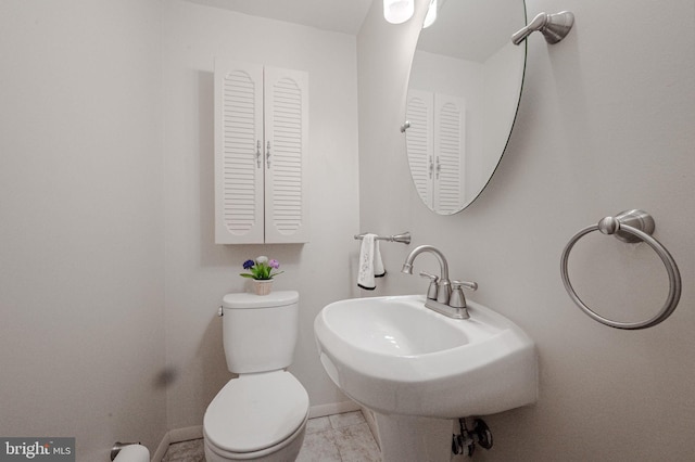 half bath featuring a sink, toilet, tile patterned flooring, and baseboards