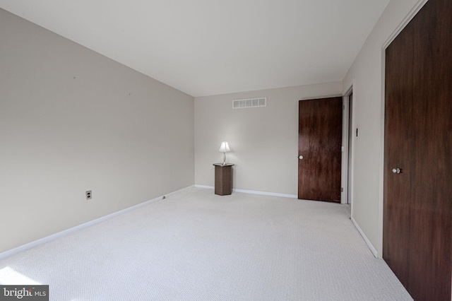 unfurnished room with visible vents, baseboards, and light colored carpet