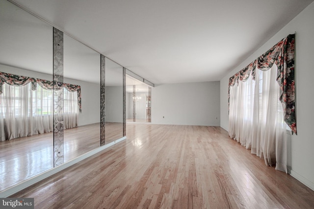 unfurnished bedroom featuring light wood-style flooring, multiple windows, a chandelier, and baseboards