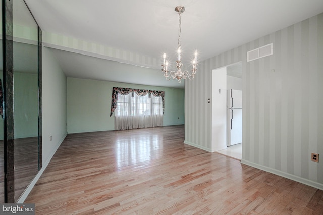 interior space featuring visible vents, baseboards, a notable chandelier, wallpapered walls, and light wood-style flooring