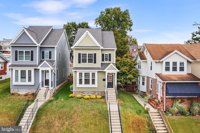 view of front of house with entry steps, a front lawn, and roof with shingles