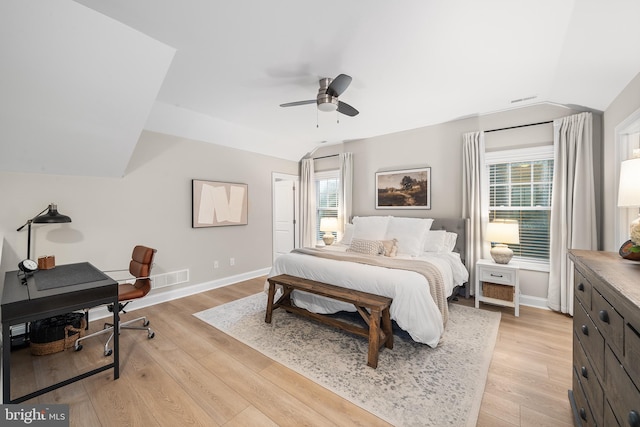 bedroom featuring light wood-style floors, multiple windows, and lofted ceiling