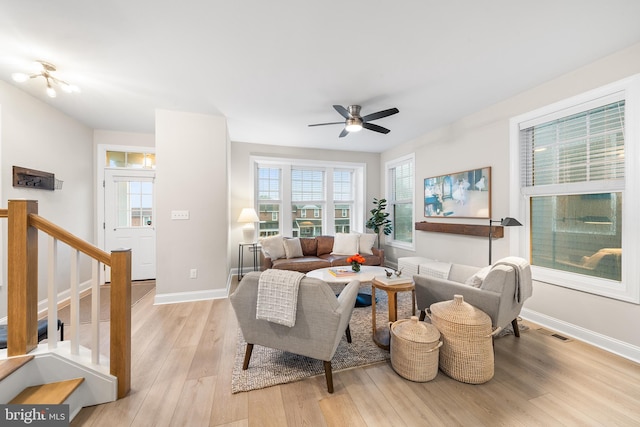 living room with ceiling fan, stairway, light wood-style floors, and baseboards