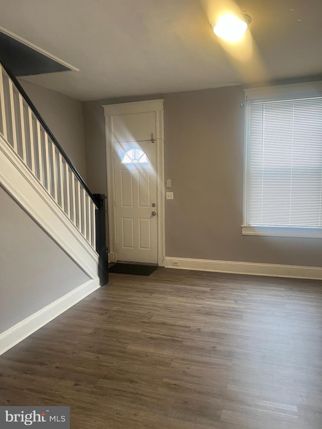foyer featuring baseboards, dark wood finished floors, plenty of natural light, and stairway