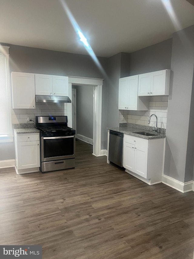 kitchen featuring under cabinet range hood, baseboards, a sink, and appliances with stainless steel finishes