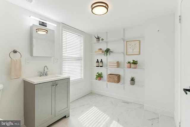 bathroom featuring baseboards, marble finish floor, and vanity