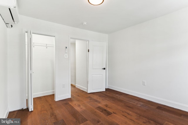 unfurnished bedroom with dark wood-type flooring, a closet, a wall mounted air conditioner, and baseboards