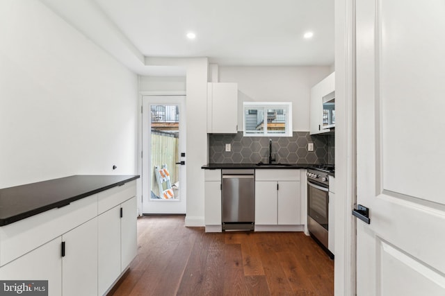 kitchen featuring dark wood-style flooring, white cabinetry, dark countertops, appliances with stainless steel finishes, and a sink