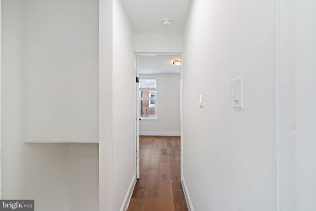 corridor with dark wood-style flooring and baseboards