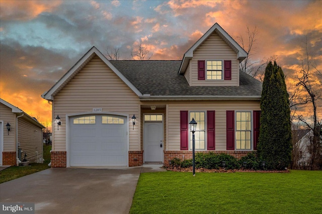 view of front of property featuring a yard, roof with shingles, brick siding, an attached garage, and concrete driveway