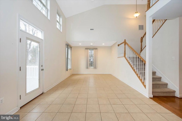 foyer featuring visible vents, baseboards, high vaulted ceiling, and stairway