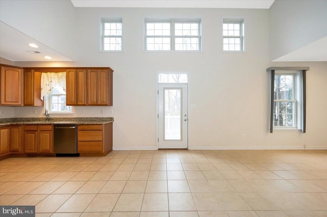 kitchen featuring stainless steel dishwasher, brown cabinets, and a high ceiling