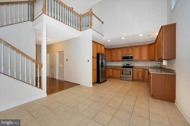 kitchen featuring baseboards, a high ceiling, recessed lighting, stainless steel appliances, and light tile patterned flooring