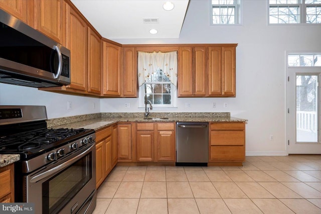 kitchen with light stone counters, light tile patterned flooring, visible vents, stainless steel appliances, and a sink