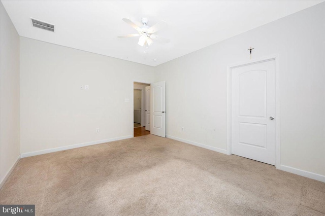 empty room with carpet floors, a ceiling fan, and visible vents