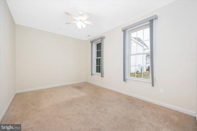 carpeted spare room with baseboards and a ceiling fan
