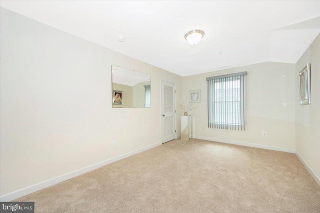 unfurnished room featuring light colored carpet and baseboards