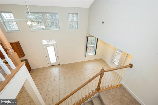 foyer with baseboards, stairway, a towering ceiling, and a healthy amount of sunlight