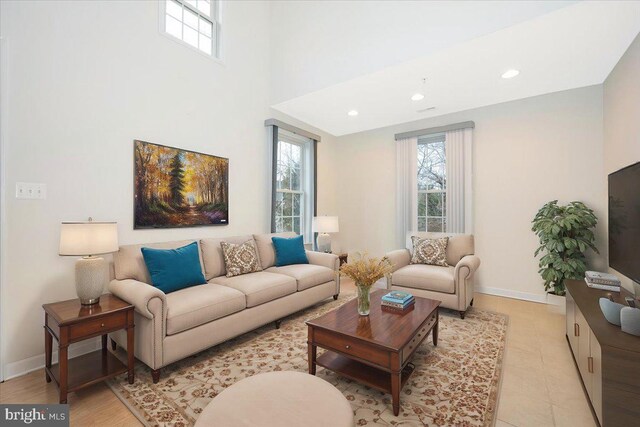 living room featuring a wealth of natural light, recessed lighting, a towering ceiling, and baseboards