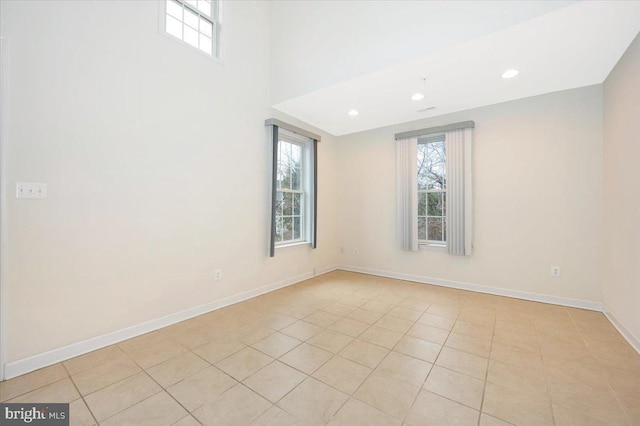 spare room with baseboards, recessed lighting, light tile patterned flooring, and a towering ceiling