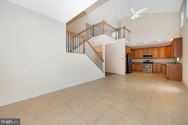 unfurnished living room featuring light tile patterned floors, high vaulted ceiling, ceiling fan, stairs, and baseboards