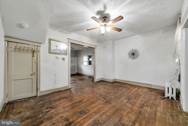 unfurnished living room featuring radiator heating unit, baseboards, a ceiling fan, and hardwood / wood-style flooring