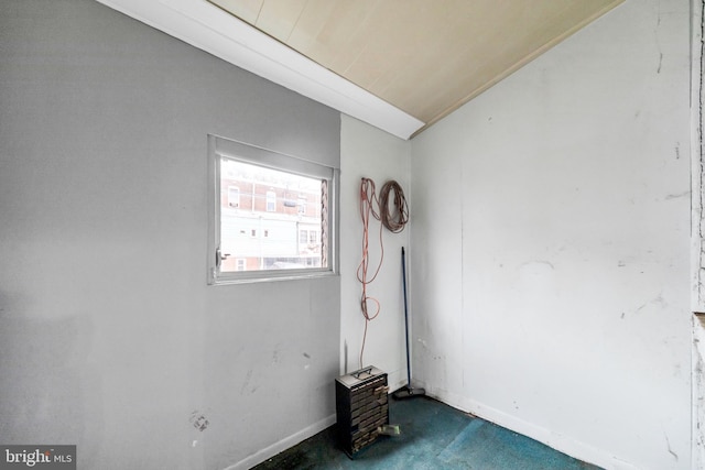 spare room with baseboards, dark colored carpet, and lofted ceiling
