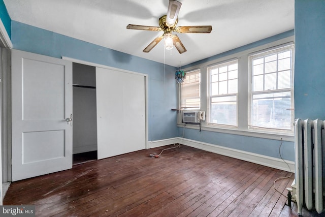 unfurnished bedroom featuring a closet, baseboards, a ceiling fan, radiator heating unit, and hardwood / wood-style floors