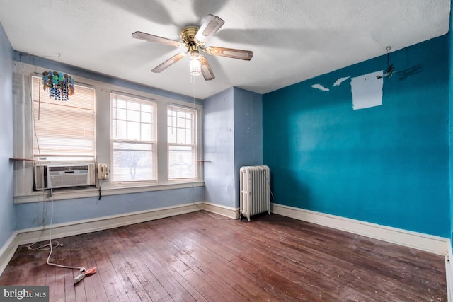 unfurnished room with baseboards, cooling unit, radiator heating unit, hardwood / wood-style floors, and ceiling fan