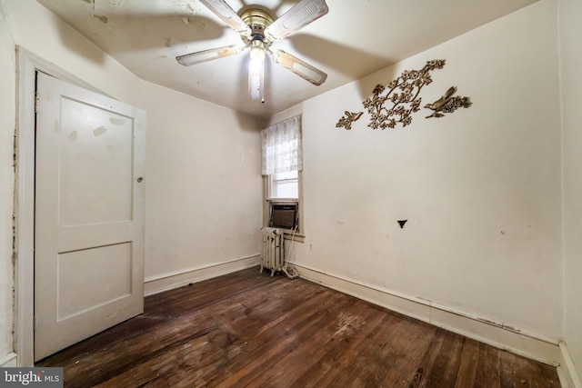 spare room featuring baseboards, cooling unit, a ceiling fan, radiator, and dark wood finished floors