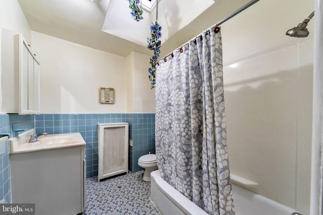 full bath with shower / bath combination with curtain, vanity, toilet, wainscoting, and tile walls