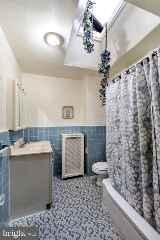 full bathroom with toilet, tile walls, a wainscoted wall, vanity, and tile patterned floors
